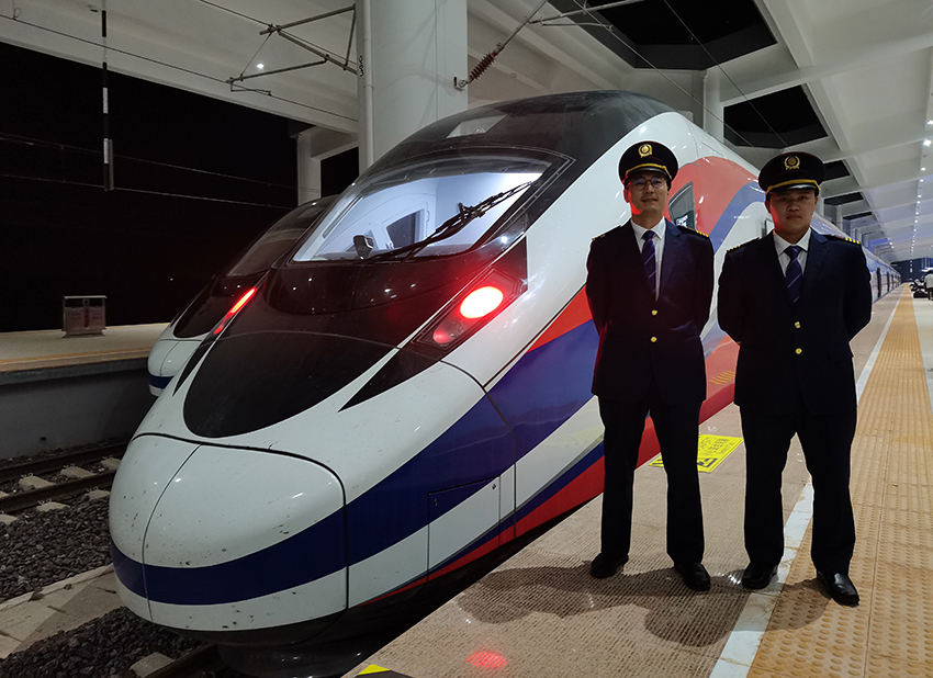 劉銀能（右一）與中國師父鄔俊鴻在動車組前合影。受訪者供圖